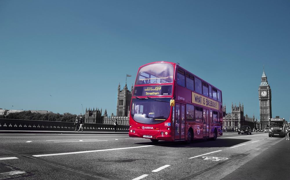 A red double-decker bus on a London street with Big Ben in the background